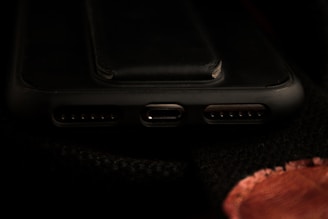 A close-up view of a smartphone's charging port area, including the USB-C port and speaker grills, with a dark background.
