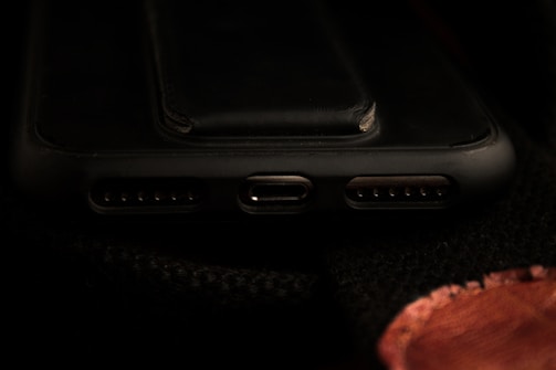 Technician using a microscope to inspect a smartphone charging port.