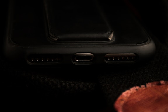 A close-up view of a smartphone's charging port area, including the USB-C port and speaker grills, with a dark background.