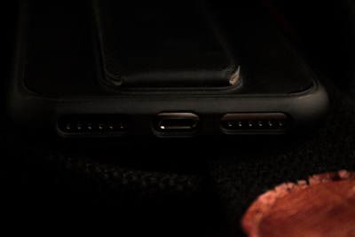 A close-up view of a smartphone's charging port area, including the USB-C port and speaker grills, with a dark background.
