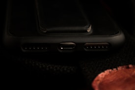 A close-up view of a smartphone's charging port area, including the USB-C port and speaker grills, with a dark background.