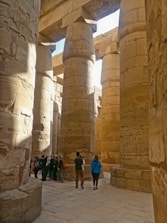 Small group photographing intricate hieroglyphs inside a Luxor temple.