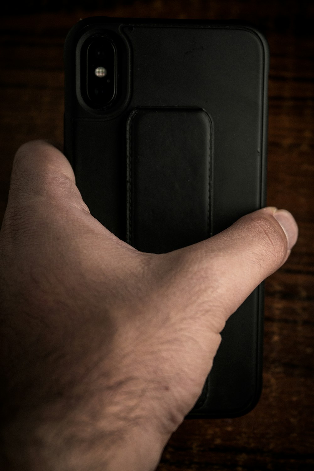 a person's hand holding a black cell phone