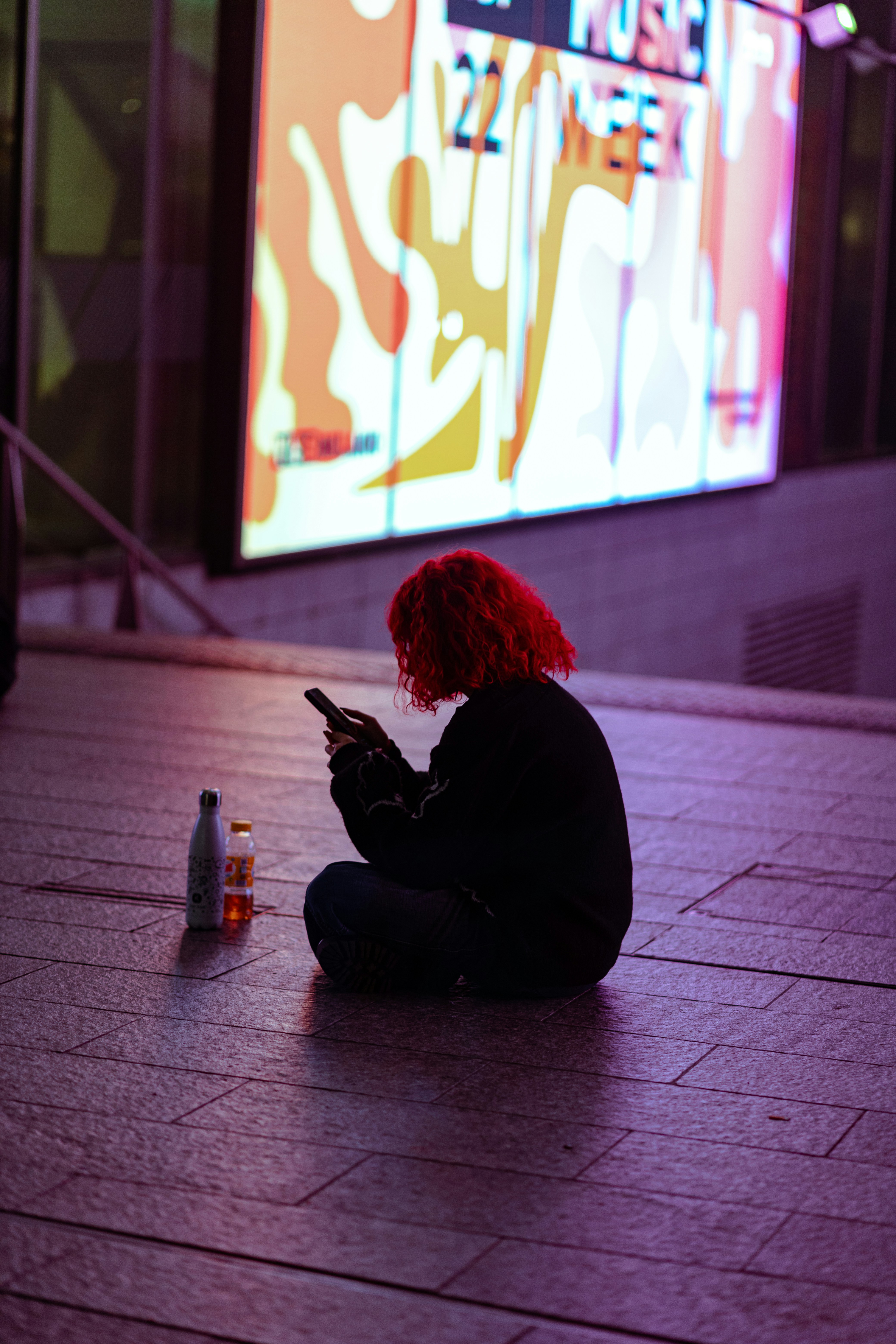 a person sitting on the ground with a cell phone