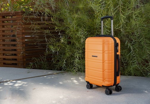 an orange piece of luggage sitting on top of a sidewalk