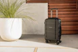 a black suitcase sitting next to a plant