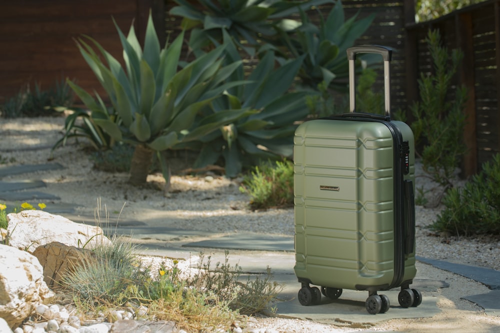 a green suitcase sitting on top of a sidewalk