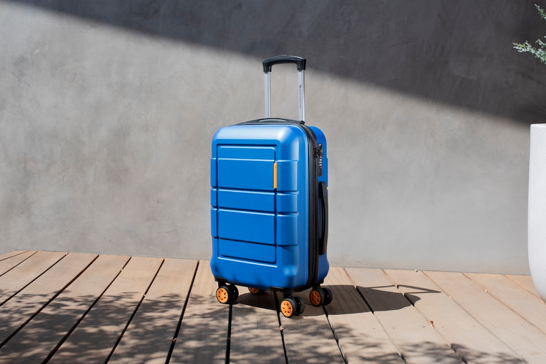 a blue suitcase sitting on top of a wooden floor, Andante airline-approved carry-on from American Green Travel (blue).