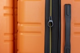an orange piece of luggage with a black handle