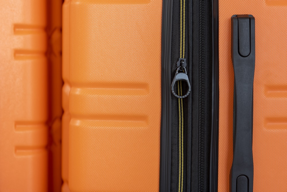 an orange piece of luggage with a black handle