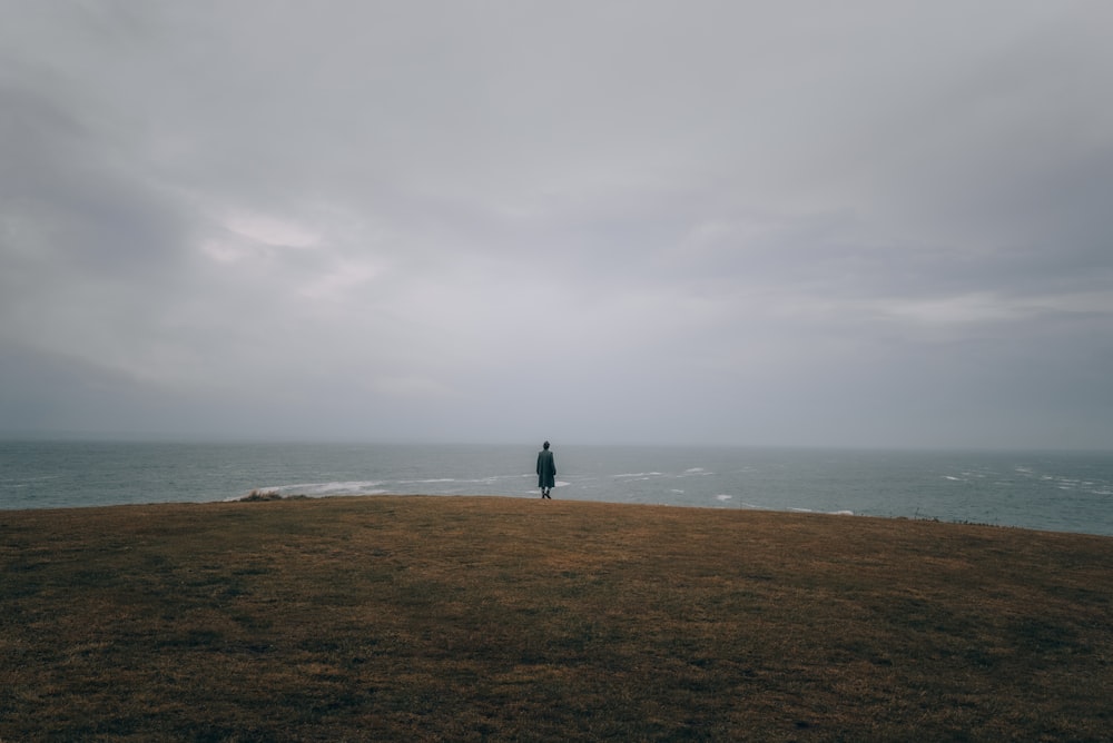 a person standing on top of a hill near the ocean