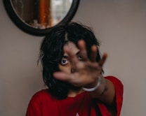 a woman making a hand gesture in front of a mirror