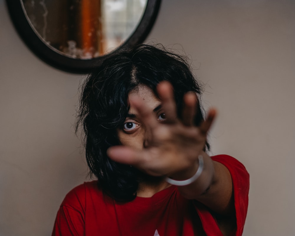 a woman making a hand gesture in front of a mirror