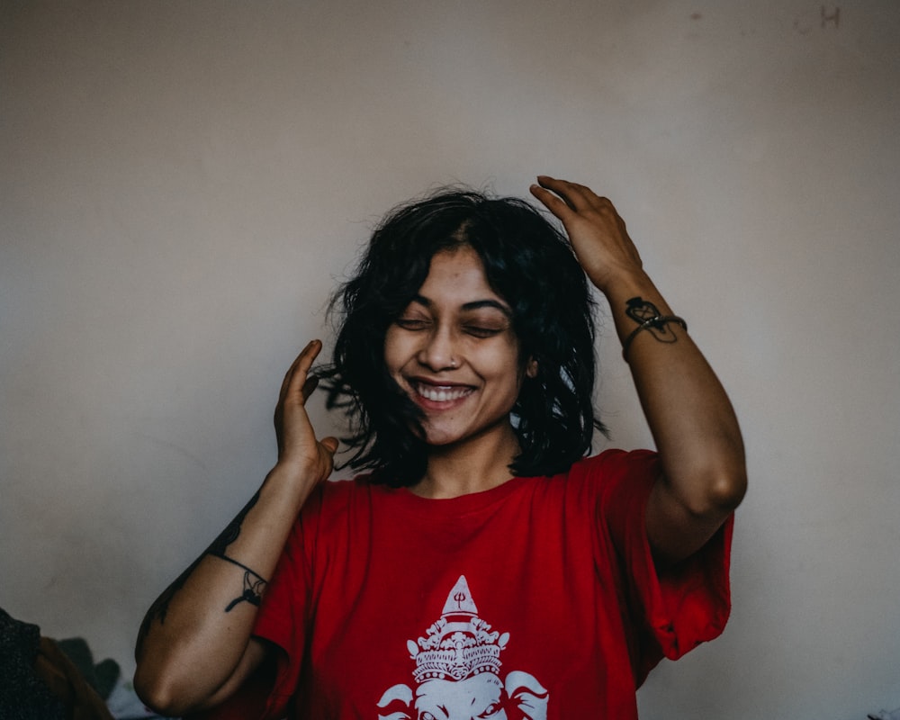 a woman is smiling and holding her hair in the air