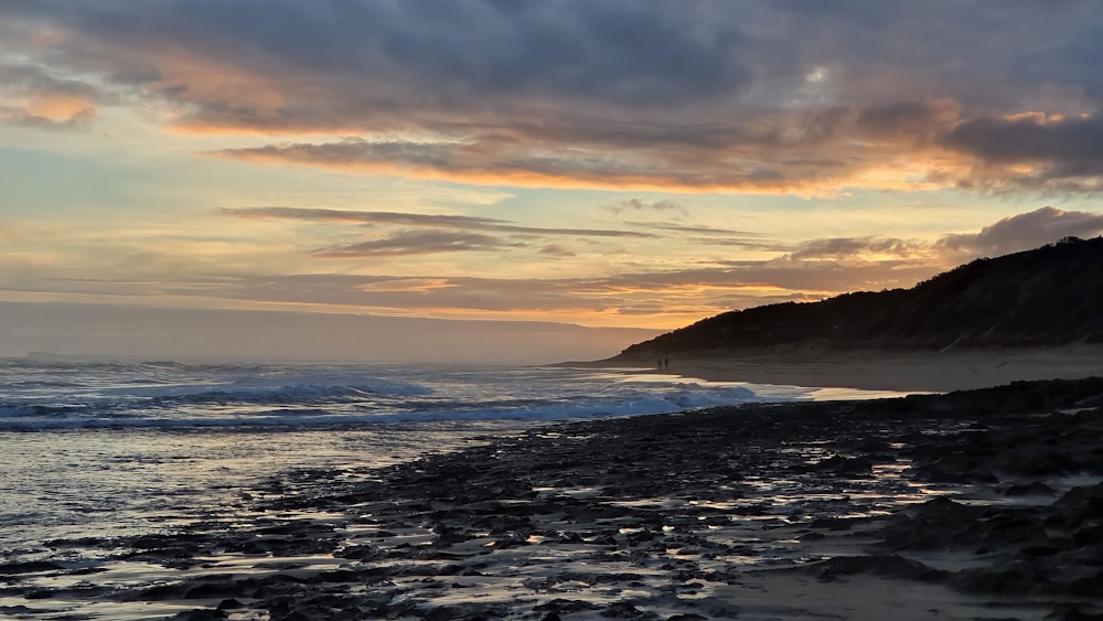 the sun is setting over the ocean and a beach