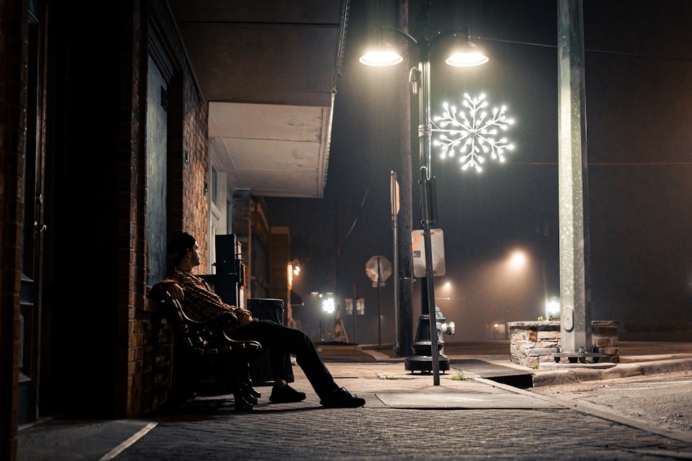 a person sitting on a bench under a street light