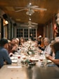 a group of people sitting at a long table