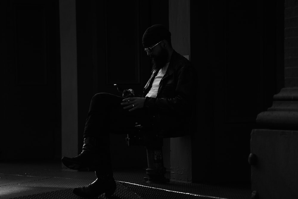 a man sitting in a chair looking at his cell phone