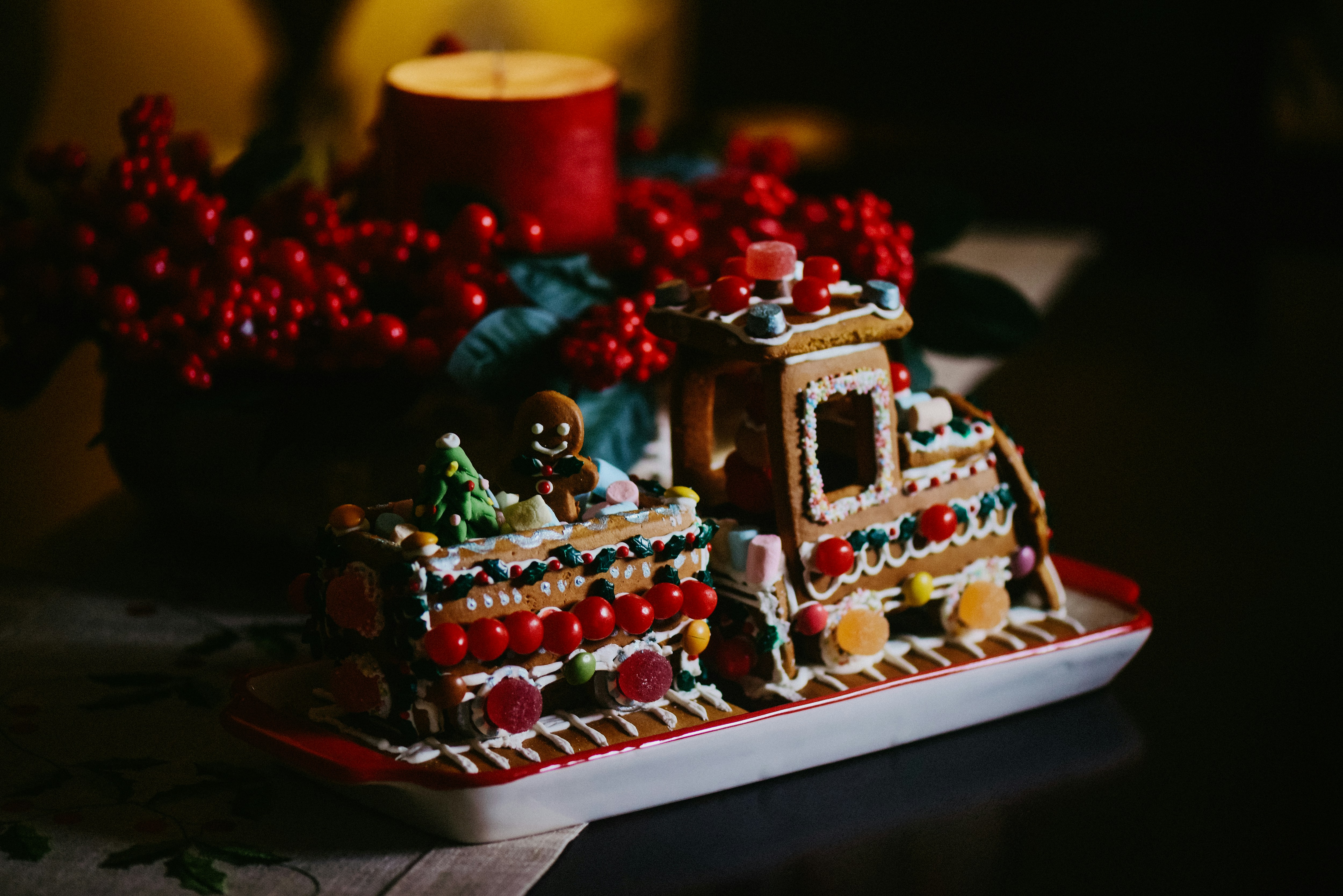 a gingerbread house with a lit candle in the background