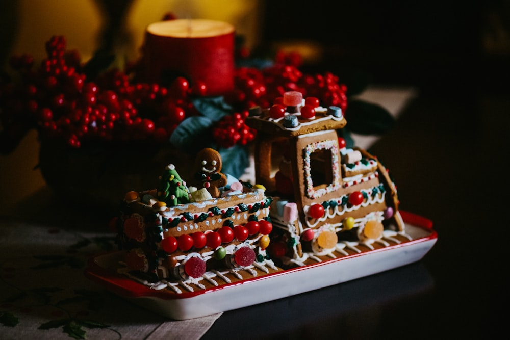 a gingerbread house with a lit candle in the background