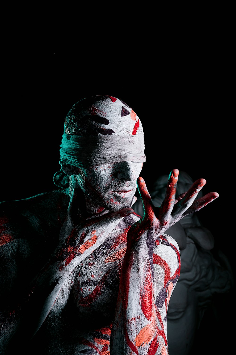 a man covered in white and red paint holding his hands up