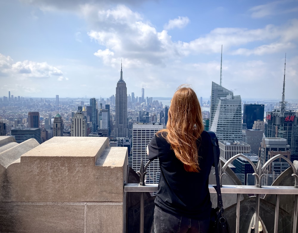Une femme debout au sommet d’un grand immeuble