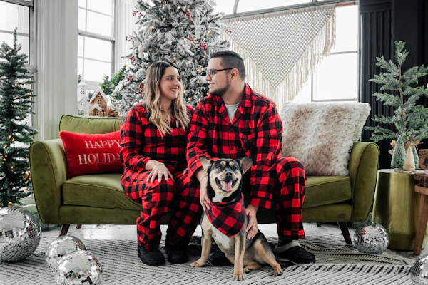 Couple in matching plaid pajamas with their dog on a holiday set