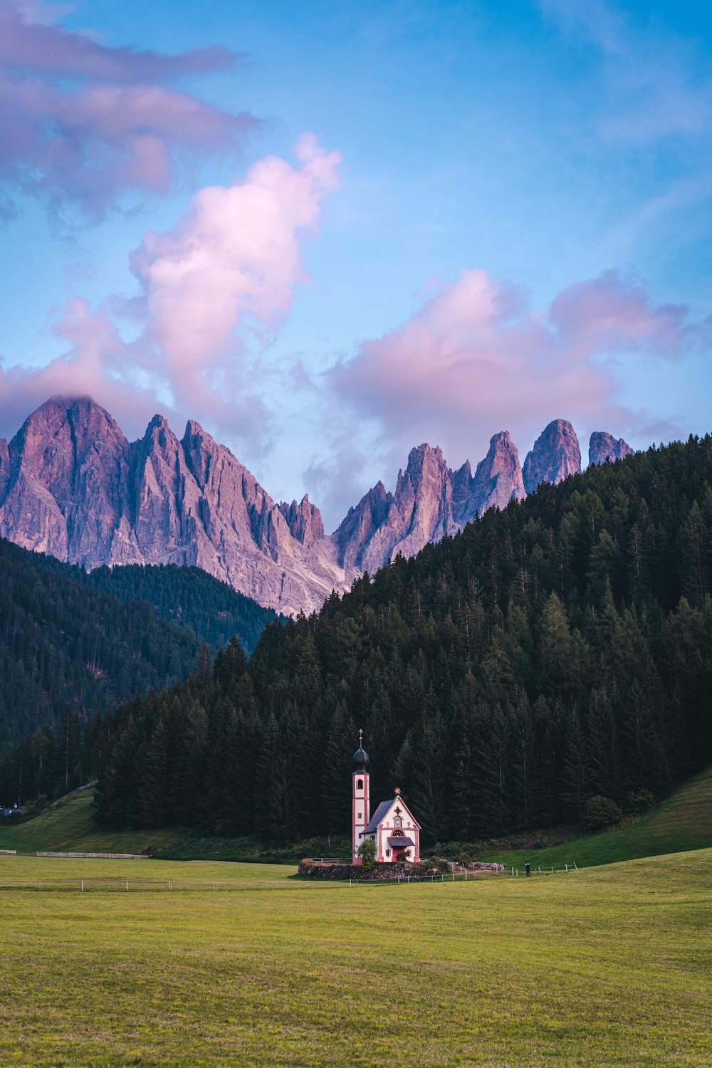 a church in a field with mountains in the background