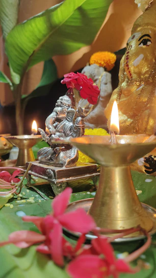 A serene prayer corner featuring a brass agarbatti stand beside softly glowing candles and fresh flowers.