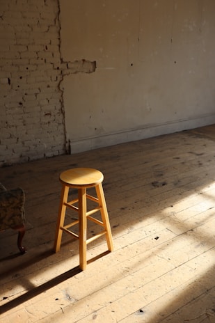 A finished wooden stool with a smooth, natural finish sitting in a cozy workshop.