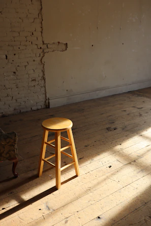Handcrafted wooden stool with a warm finish in a cozy apartment nook.