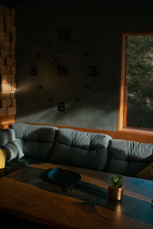 A cozy living room corner featuring a wall clock made of resin art, softly lit by natural light.