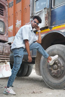 A confident truck driver smiling beside a large rig on a clear highway, ready for the next load.