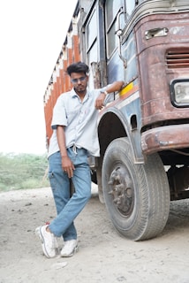 A rugged man leaning against a pickup truck, sporting a rowdy.co shirt with a vintage western print.