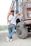 A rugged trucker wearing a faded Libertad Ruda hoodie standing beside his big rig at sunset.