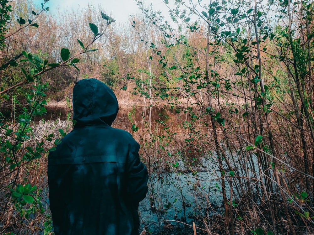 a person in a hooded jacket looking at a river