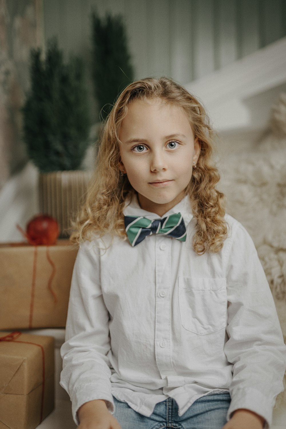 a little girl wearing a bow tie sitting on a couch