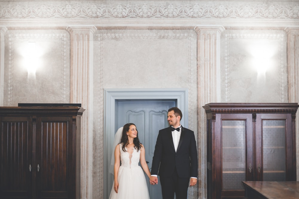 a bride and groom standing in front of a blue door