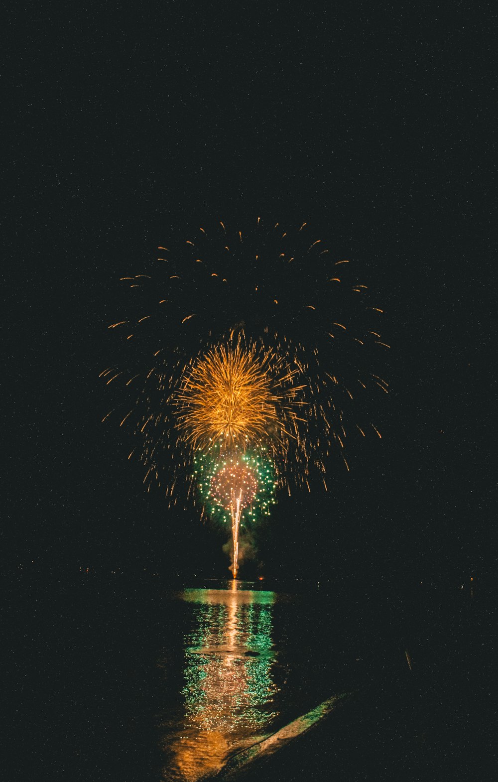 a firework display in the night sky over a body of water