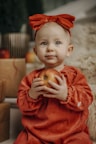 a little girl in a red dress holding an apple