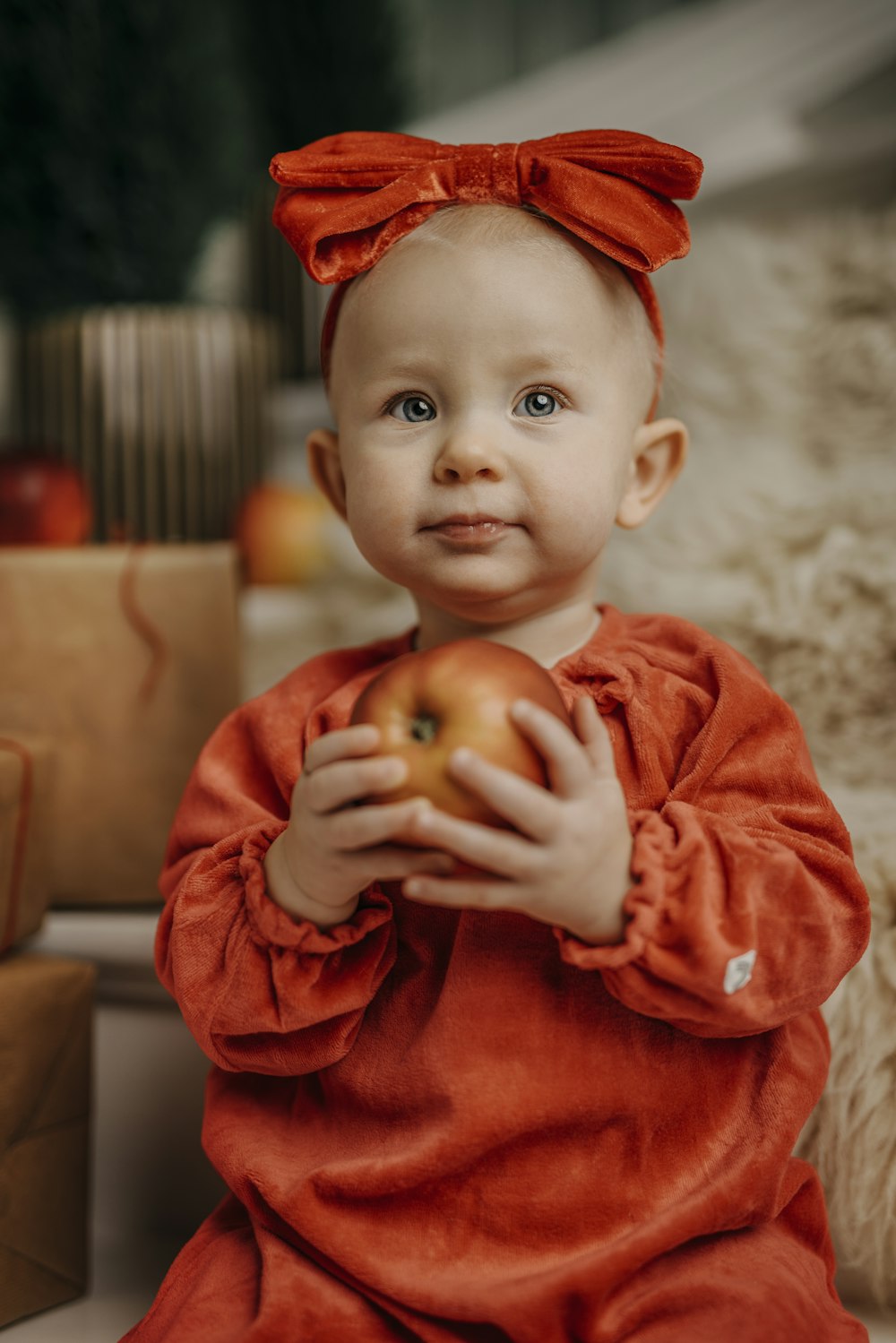 a little girl in a red dress holding an apple
