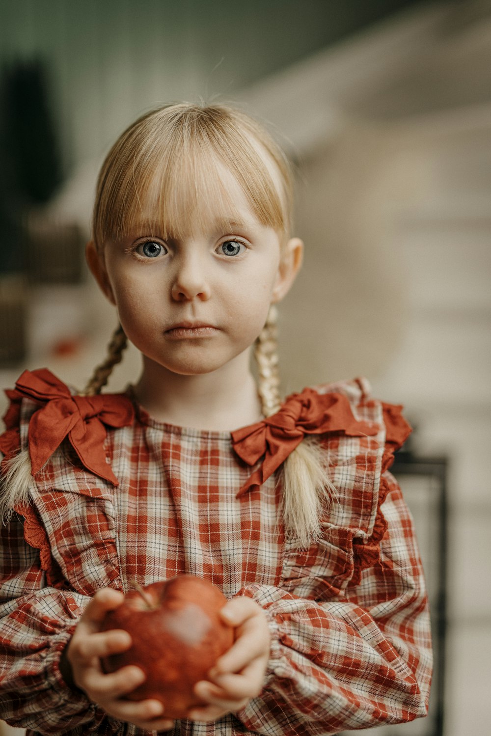 a little girl holding an apple with a sad look on her face