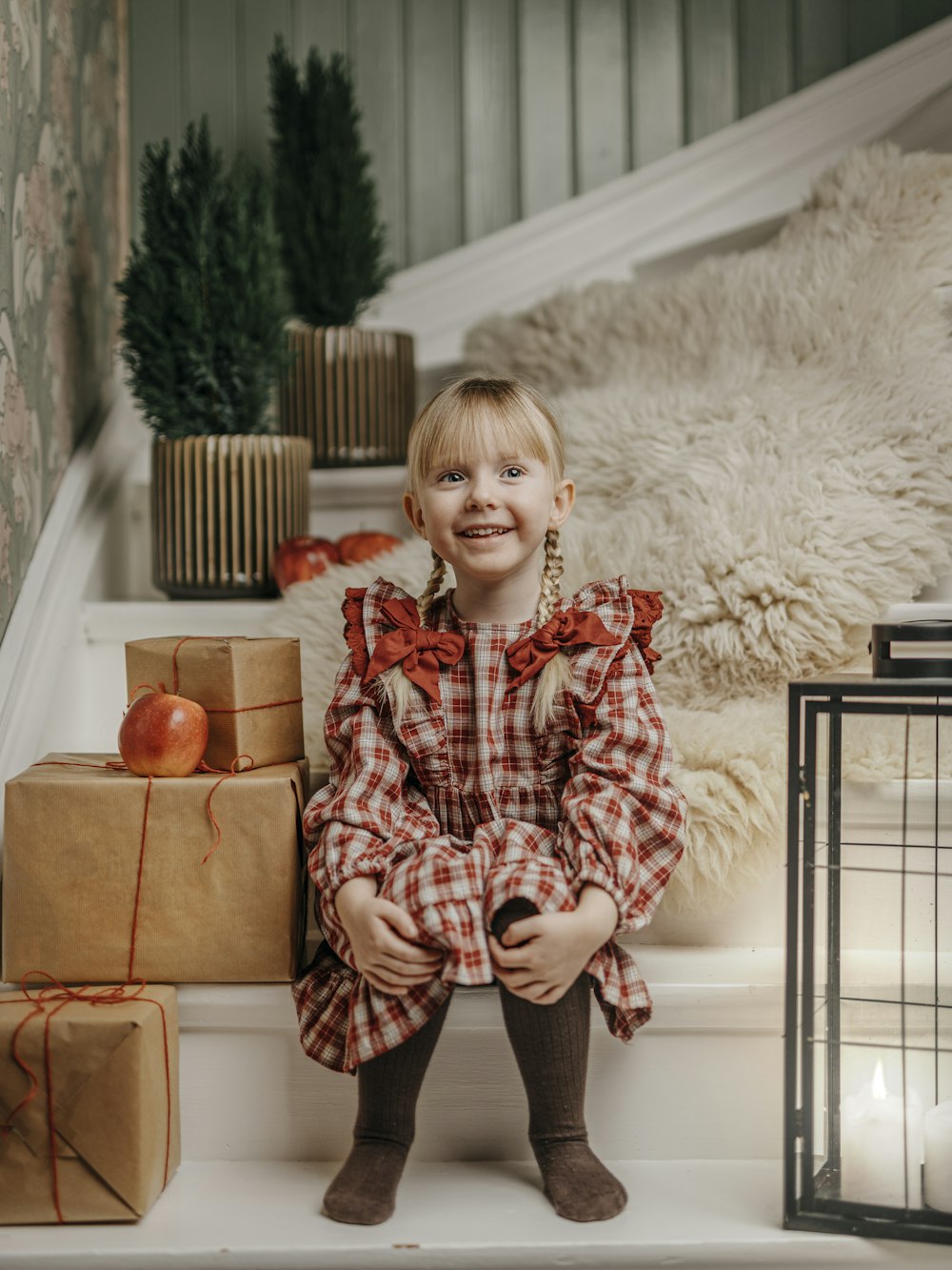 a little girl sitting on the steps with presents