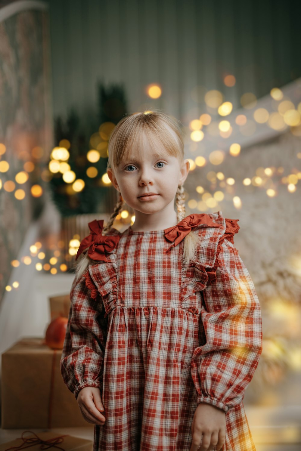 a little girl standing in front of a christmas tree