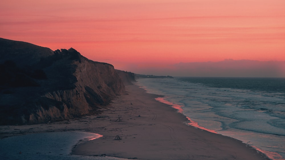 the sun is setting over the ocean and the beach