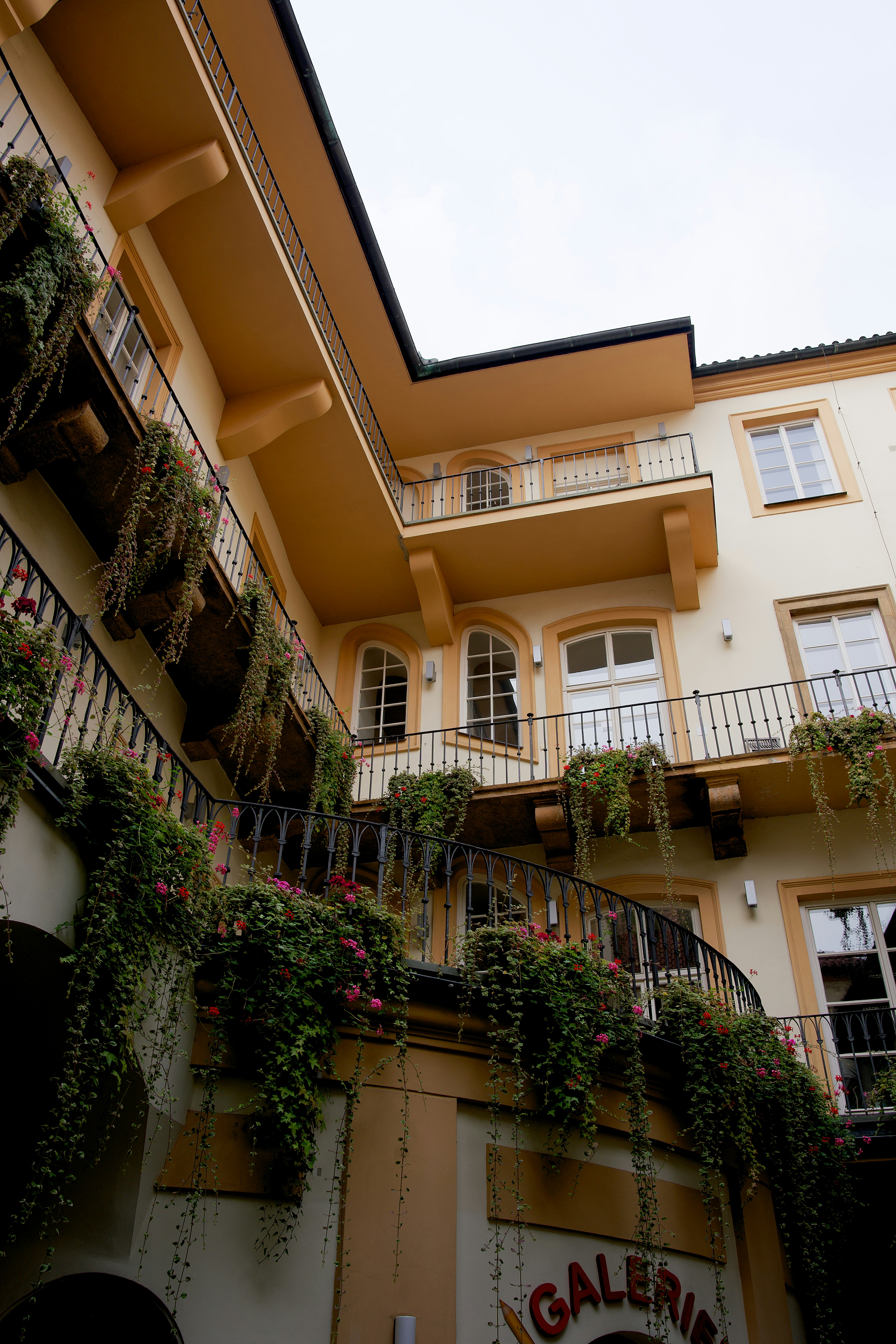 Un edificio alto con un sacco di fiori che crescono sui suoi balconi