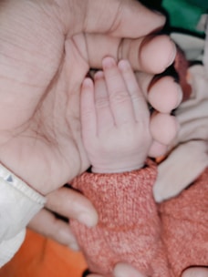 Close-up of a drag artist smiling warmly while holding a tiny baby mitten.