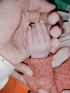 Close-up of sproutbae’s gentle cotton mittens resting beside a baby's tiny hands.