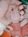Close-up of a tiny hand holding a mint green baby toy gently.