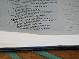 A close-up view of an open book displaying printed text. The page is focused on a section that contains numbered paragraphs, with some text in bold. The book's pages are slightly curved, and a green ribbon marker is visible at the bottom.